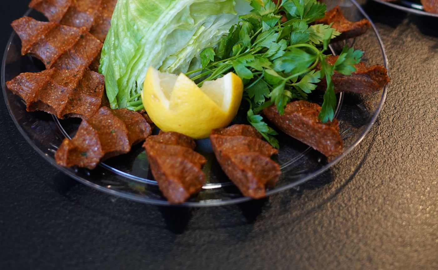 Çiğ köfte portion on a plate with lettuce, parsley and lemon wedges